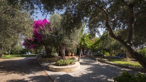 A garden with trees, a paved area, and outdoor seating. - Orionas Village (Chania)