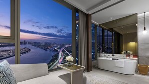 A modern hotel room with a large window offering a city view, a sofa, a small table with a vase, and a separate bathroom area. - InterContinental Quanzhou by IHG (Quanzhou)