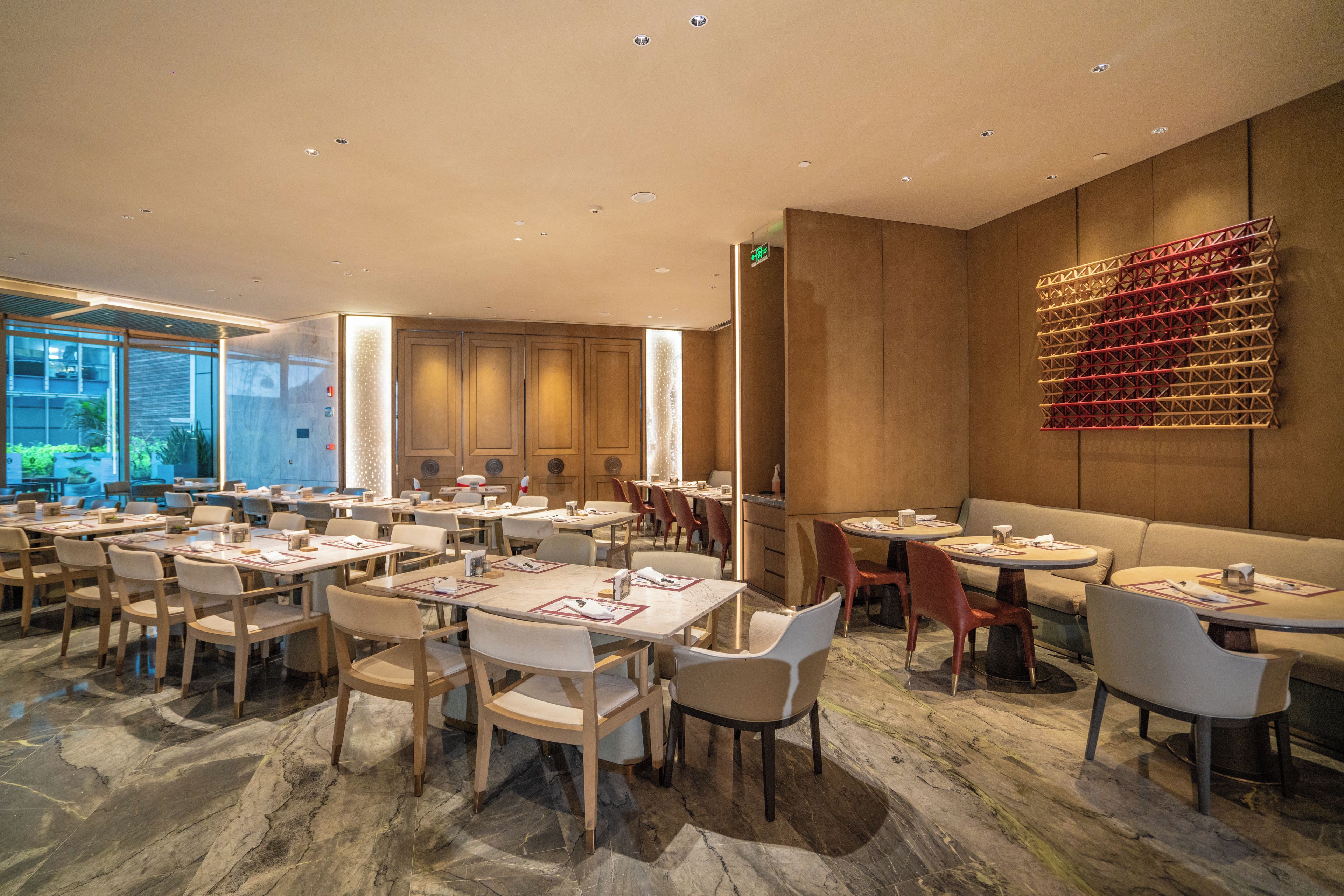 A modern restaurant interior with marble flooring, wooden tables, and chairs.