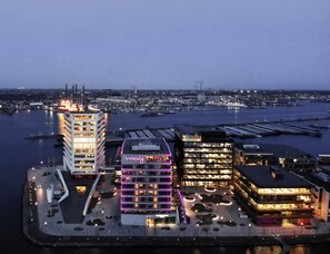 A waterfront hotel with multiple buildings, a marina, and a cityscape in the background.