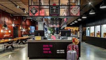 A reception area with a check-in counter, seating area, and a staircase leading to an upper level.