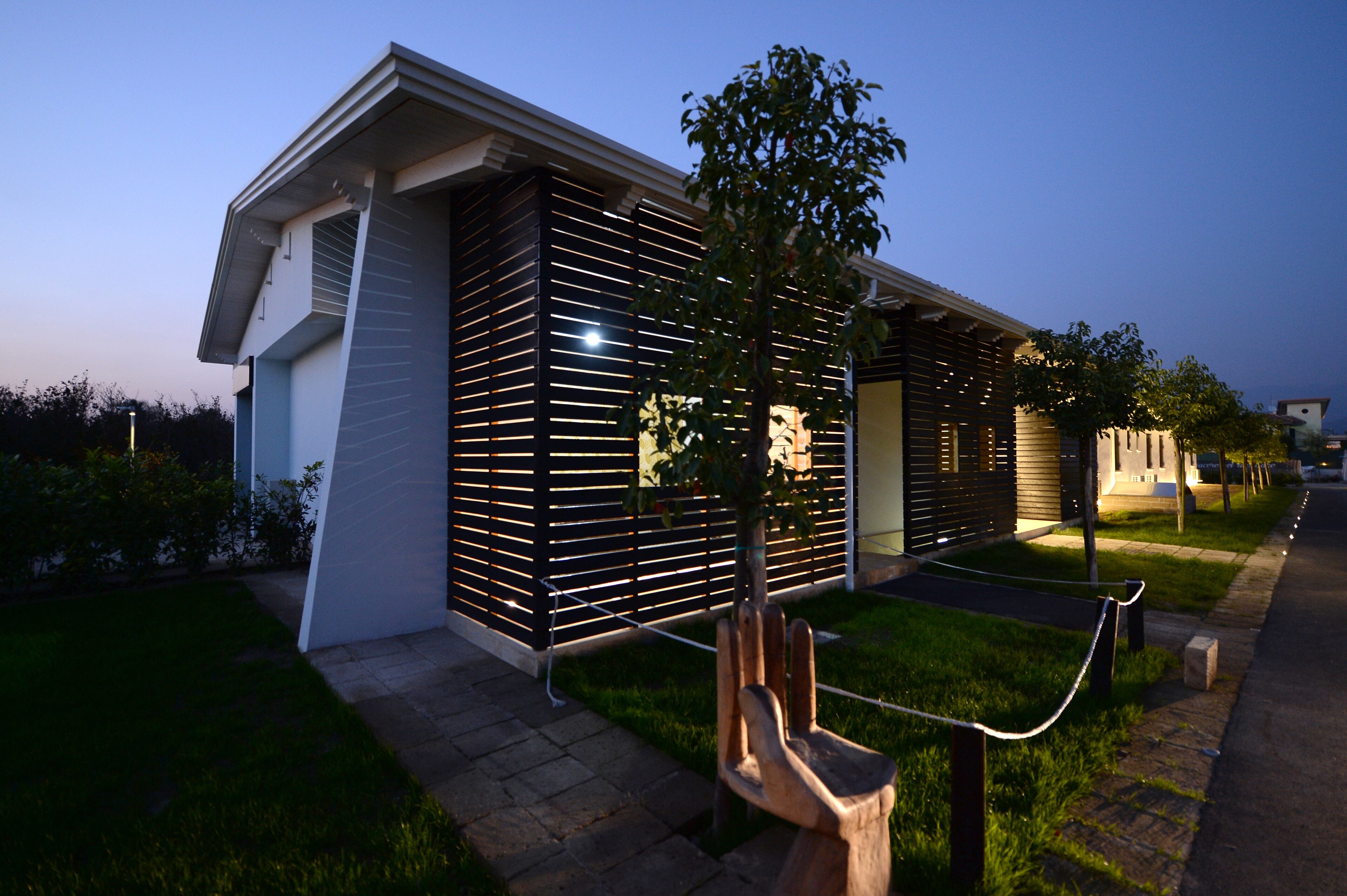 Un bâtiment moderne doté d’une façade à lattes, d’un banc en bois et d’une barrière en corde.