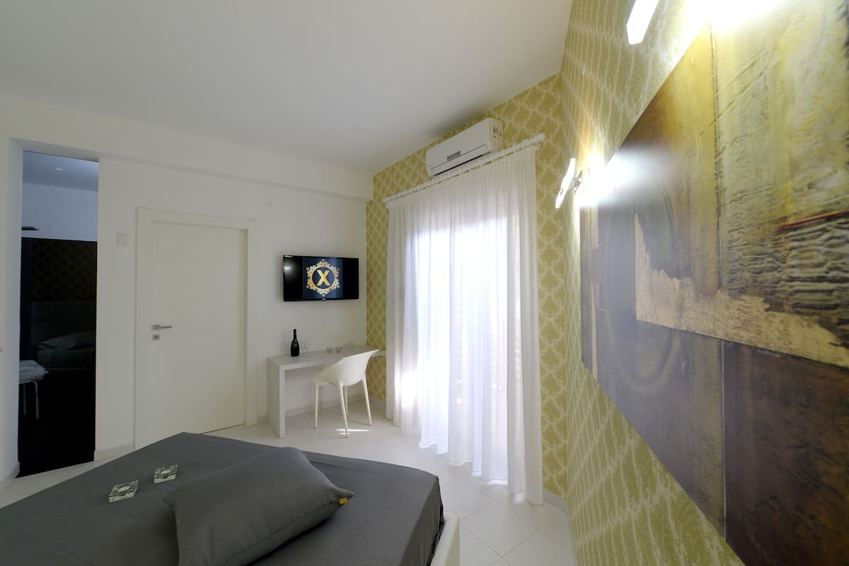 A bedroom with a bed, a desk, and a TV.