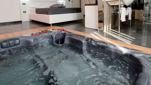 A modern bathroom with a large bathtub, a separate shower area, and a vanity with a mirror. - X Hotel (Saviano)