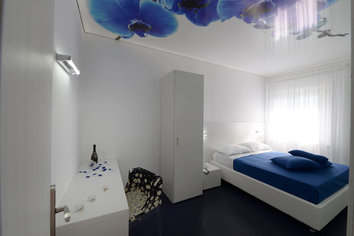 A modern hotel room with a bed, a desk, and a chair.