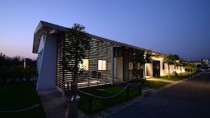 A modern building with a slatted facade, a well-maintained lawn, and a gated entrance. - X Hotel (Saviano)