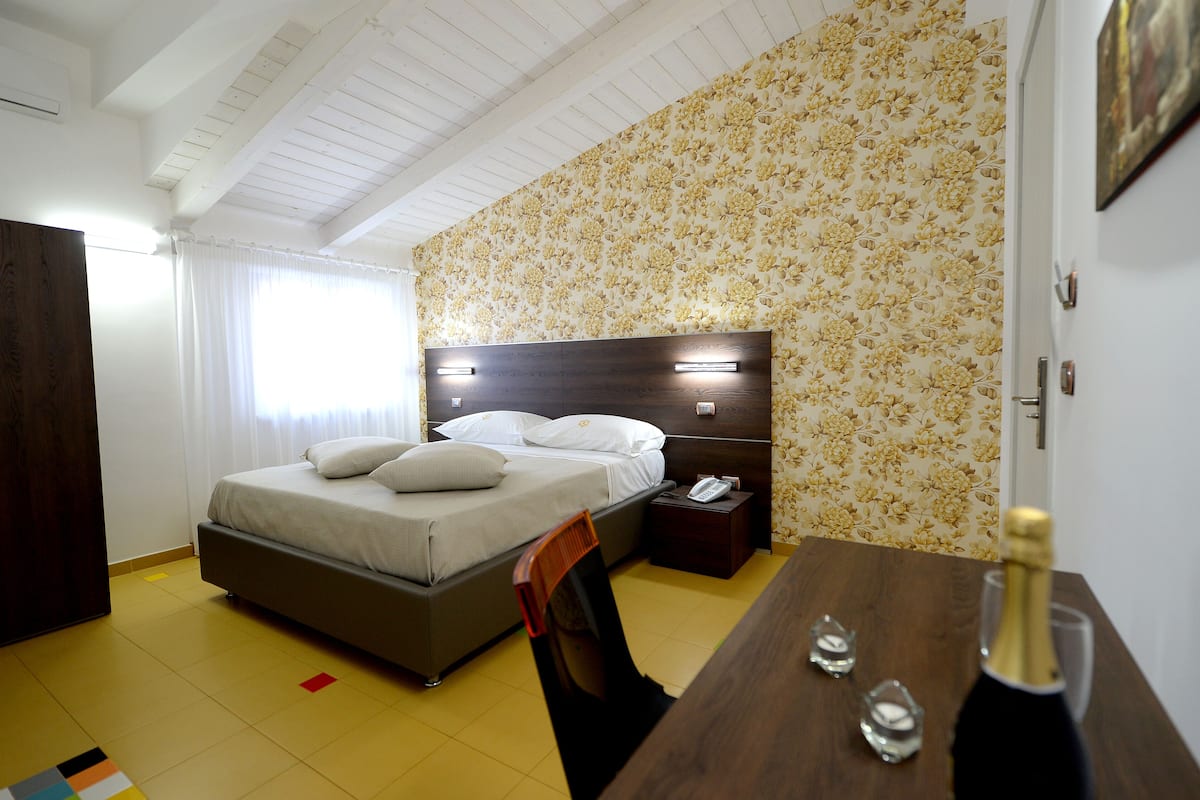 A bedroom with a bed, bedside table, and a desk with a chair.