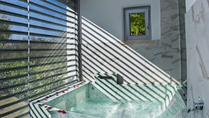 A spa area with a large, freestanding hot tub and a smaller, adjacent tub. - X Hotel (Saviano)