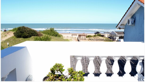 A coastal view with a beach, a blue building, and a wooden deck with white balustrades. - Ivamar Hotel & Apart (Ostende)