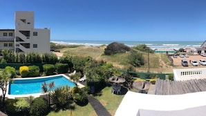 A pool area with a view of the beach, surrounded by buildings and greenery. - Ivamar Hotel & Apart (Ostende)