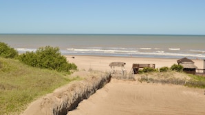 A beach with a wooden structure and a small hut, surrounded by sand dunes and sparse vegetation. - Ivamar Hotel & Apart (Ostende)