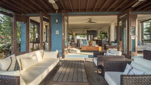 An open-plan living area with a wooden ceiling, a sofa, a coffee table, wicker chairs, and a kitchen in the background. - Luxury Oceanfront Villa w/Breathtaking Views! Infinity Edge Pool! (Llandovery, Laughlands)