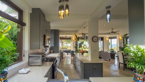 A modern kitchen with stainless steel appliances, a dining area with a view, and a living space with a ceiling fan. - Luxury Oceanfront Villa w/Breathtaking Views! Infinity Edge Pool! (Llandovery, Laughlands)