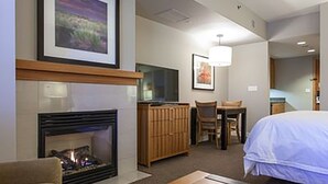 A hotel room with a fireplace, a bed, a desk, and a chair. - Monache, Mammoth Village, Luxury Studio (Mammoth Lakes)