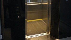 Un ascenseur avec un intérieur métallique et une ligne de sécurité jaune peinte sur le sol.