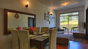 Un coin repas avec une table dressée pour quatre personnes, un canapé et un balcon avec vue.