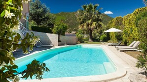 A rectangular swimming pool with a tiled edge, surrounded by lounge chairs and a palm tree. - A spacious, modern villa with a private pool (Cagliari)
