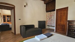 A bedroom with a large bed, a wooden ceiling, a green rug, a sofa, a dresser, and a window with curtains. - FARMHOUSE WITH PANORAMIC POOL IN PERUGIA/ASSISI IDEAL FOR GROUPS FOR 22 PLACES (Perugia)