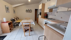 A compact kitchen with a dining table, chairs, a coffee machine, and a stove. - Maisonette 2 persons   (Biscarrosse)