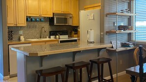 A modern kitchen with wooden cabinets, a stainless steel microwave, a built-in oven, and a large island with bar stools. - 3 Bedroom Incline Village Retreat Next to Championship Golf Course (IVGID)