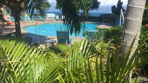 A pool area with lounge chairs and palm trees. -   OCEANFRONT WEST MAUI LOCATION 2 BDRM 2 1/2 BATH, STEPS TO THE BEACH. (Kahana)