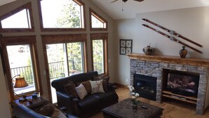 Una sala de estar con chimenea de piedra, sofá de cuero y televisión.