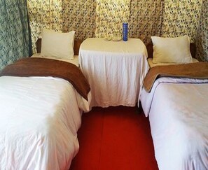 A hotel room with two single beds, a small table, and a red carpet. - Wonderland Tourist Camp (Leh)