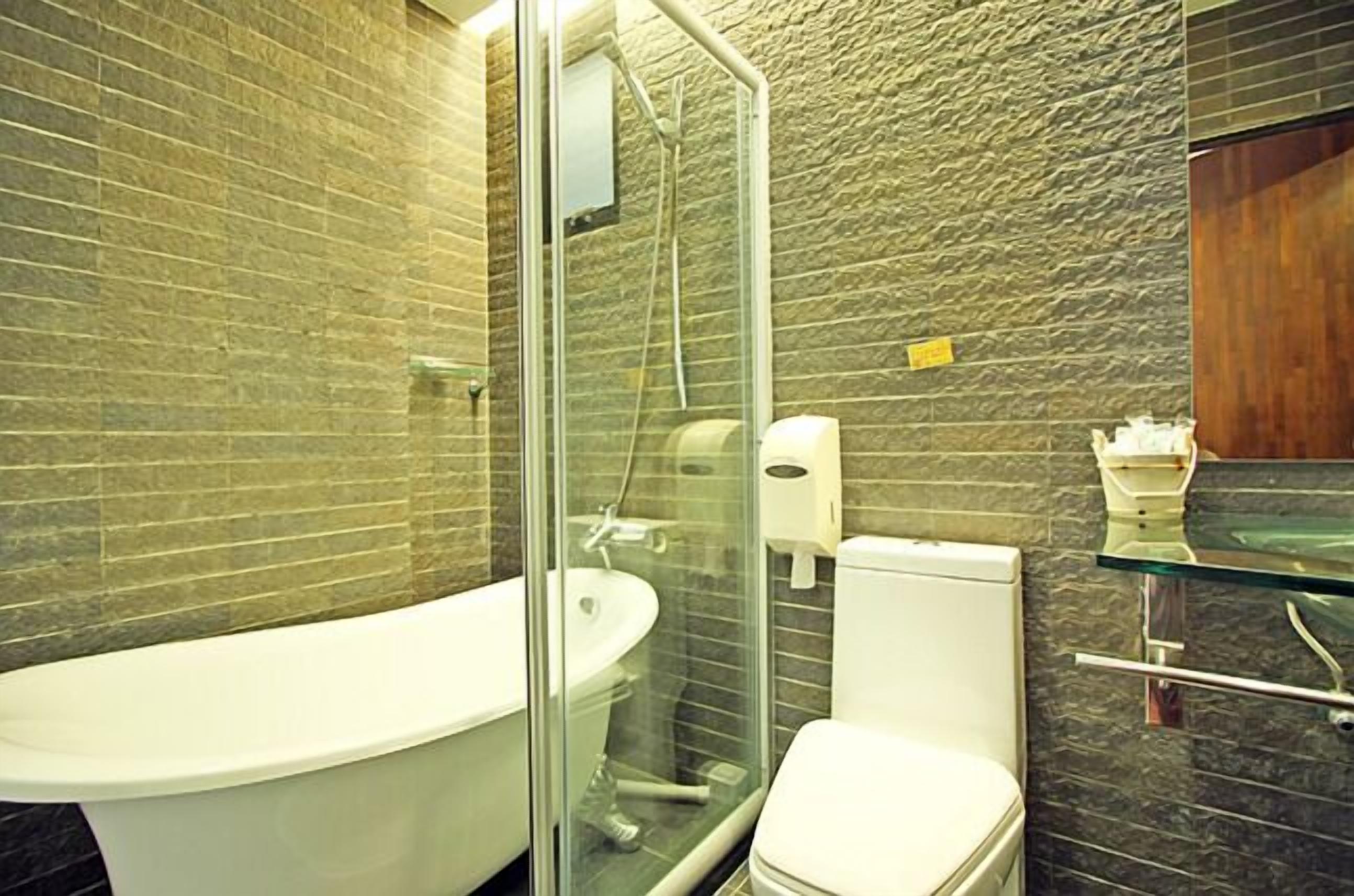 A modern bathroom with a glass-enclosed shower, a white bathtub, and a toilet.