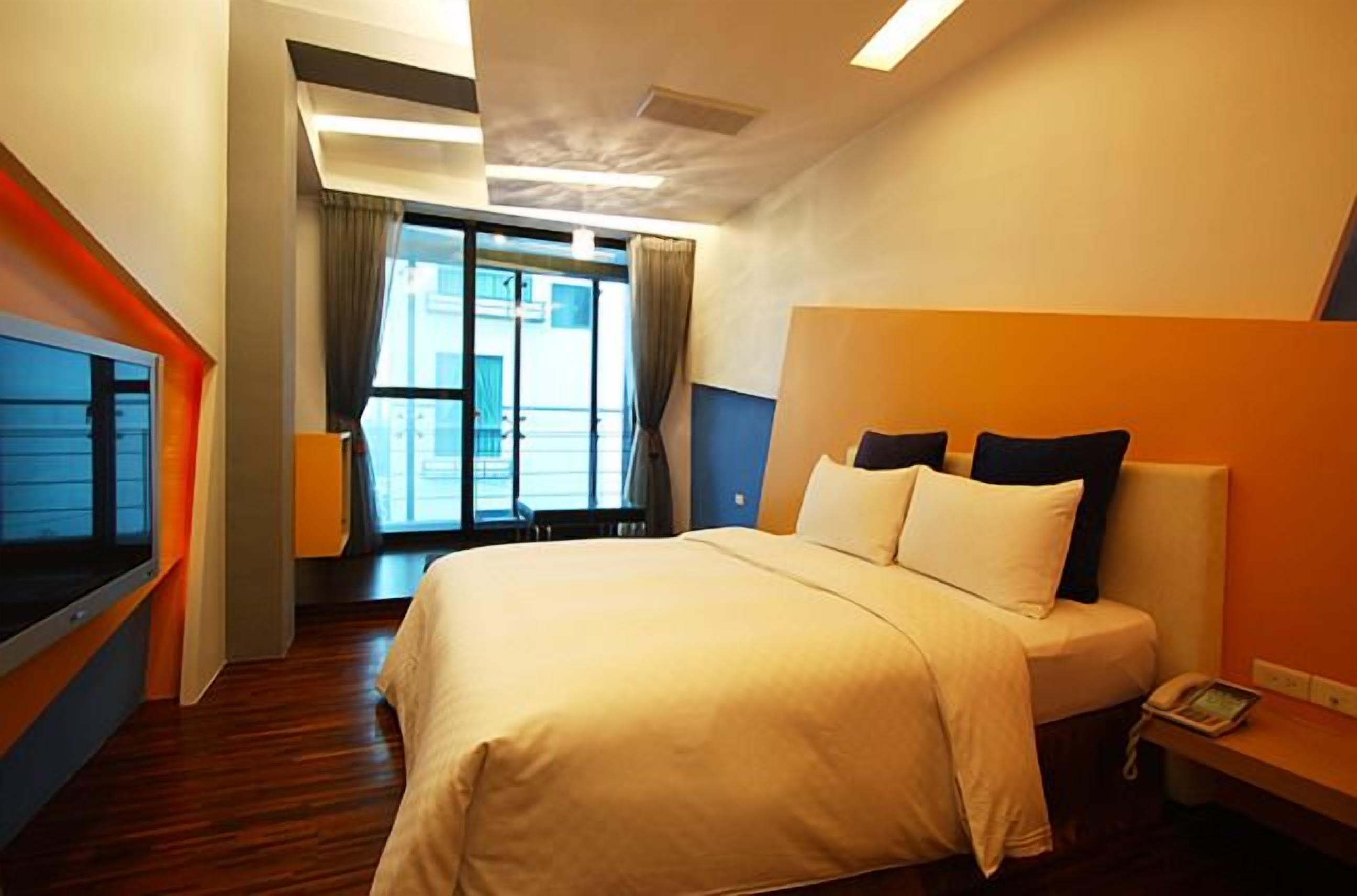 A hotel room with a large bed, a TV, and a view of the outside.