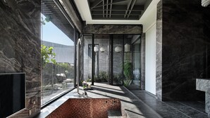 A modern bathroom with a large bathtub, marble walls, and a glass shower enclosure. - Ease Motel Taichung (Taichung)