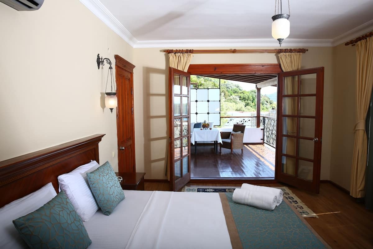 A bedroom with a large bed, a wooden headboard, and a view of an outdoor patio with a table and chairs.