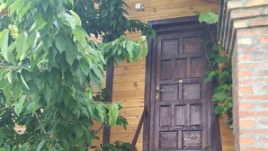 A wooden staircase leading to a dark wooden door, surrounded by greenery. - Green Set (Belgrade)