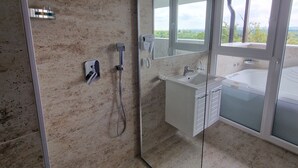 A modern bathroom with a glass-enclosed shower, a large mirror, and a view of the outdoors.