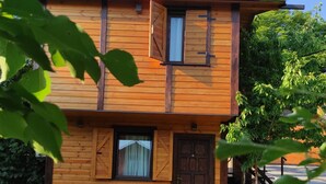 A two-story wooden house with a front door, a window with shutters, and a small porch area. - Green Set (Belgrade)