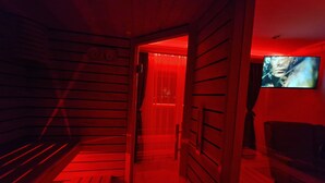 A sauna room with wooden benches and a television screen displaying a movie. - Green Set (Belgrade)