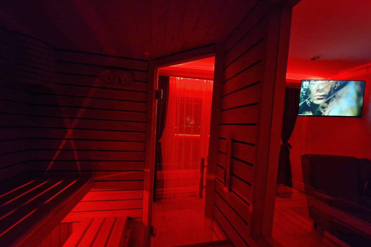 A sauna room with wooden benches and a television screen displaying a movie.