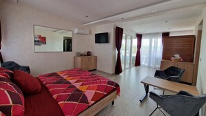 A modern hotel room with a large bed, a desk, a chair, a wardrobe, a mirror, and a television. - Green Set (Belgrade)