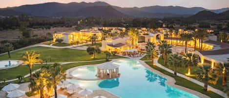 Un resort con una amplia piscina, numerosas habitaciones y palmeras.