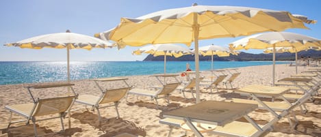 PĂ„ stranden, vit sandstrand, solstolar och parasoller