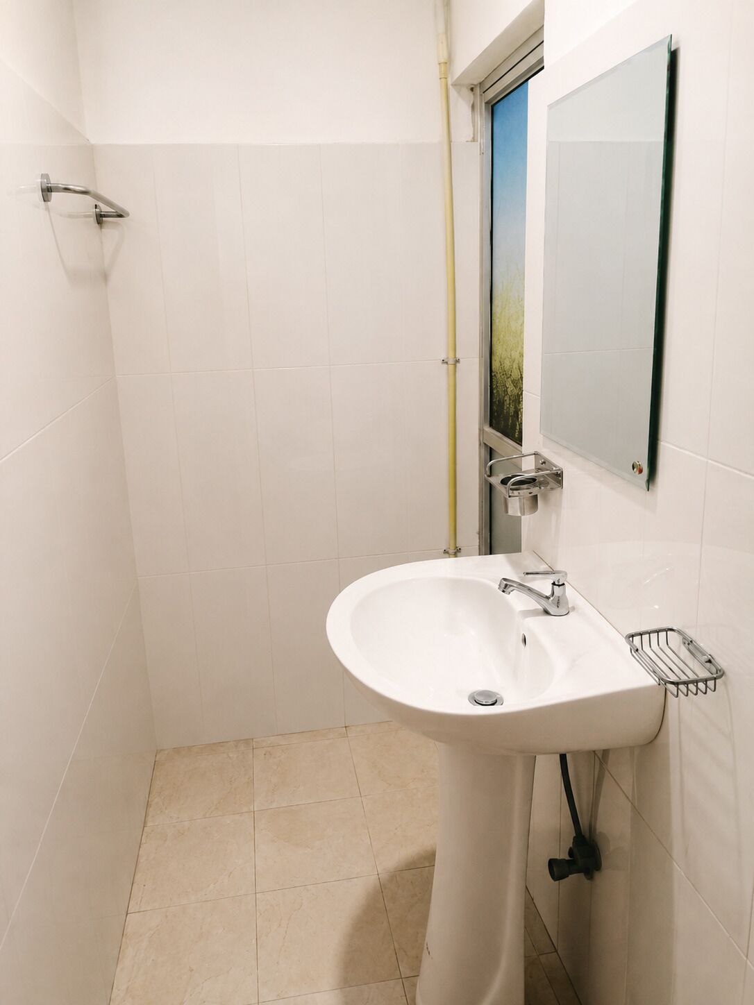 A bathroom with a white sink, a mirror, and a shower area.