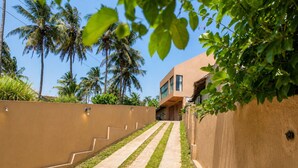 A modern building with a concrete staircase leading to a flat-roofed structure, surrounded by palm trees and greenery. - Villa Yuvin (Dondra)