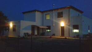 A two-story building with a flat roof, a visible entrance, and a small porch area. - Alma bed & breakfast (Sennariolo)