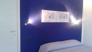 A room with a blue wall, a white door, and a bed with a white blanket. - Alma bed & breakfast (Sennariolo)