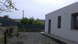 A residential area with a white building, a stone wall, and a green fence. - Alma bed & breakfast (Sennariolo)