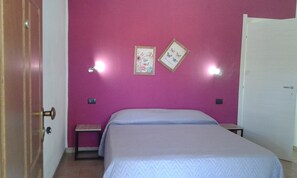 A bedroom with a bed, two wall-mounted light fixtures, and two framed pictures. - Alma bed & breakfast (Sennariolo)