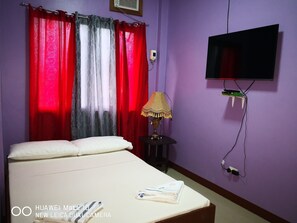 A hotel room with a bed, a TV mounted on the wall, and a lamp on a side table. - A's Azotea de Bohol (Tagbilaran)