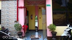 A building entrance with a stone facade, a red and yellow color scheme, and a Honda scooter parked outside. - A's Azotea de Bohol (Tagbilaran)