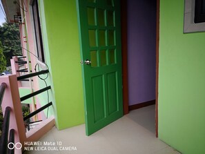 A green door with a window, a pink railing, and a tiled floor. - A's Azotea de Bohol (Tagbilaran)