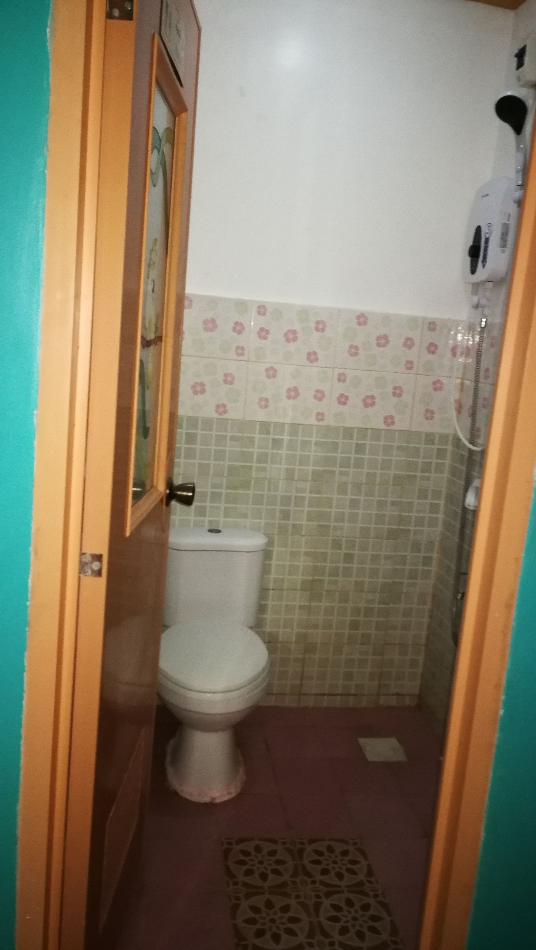 Un baño pequeño con inodoro, ducha y piso estampado.
