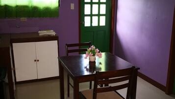 Uma área de refeições com uma porta verde, um armário branco e uma mesa com cadeiras.